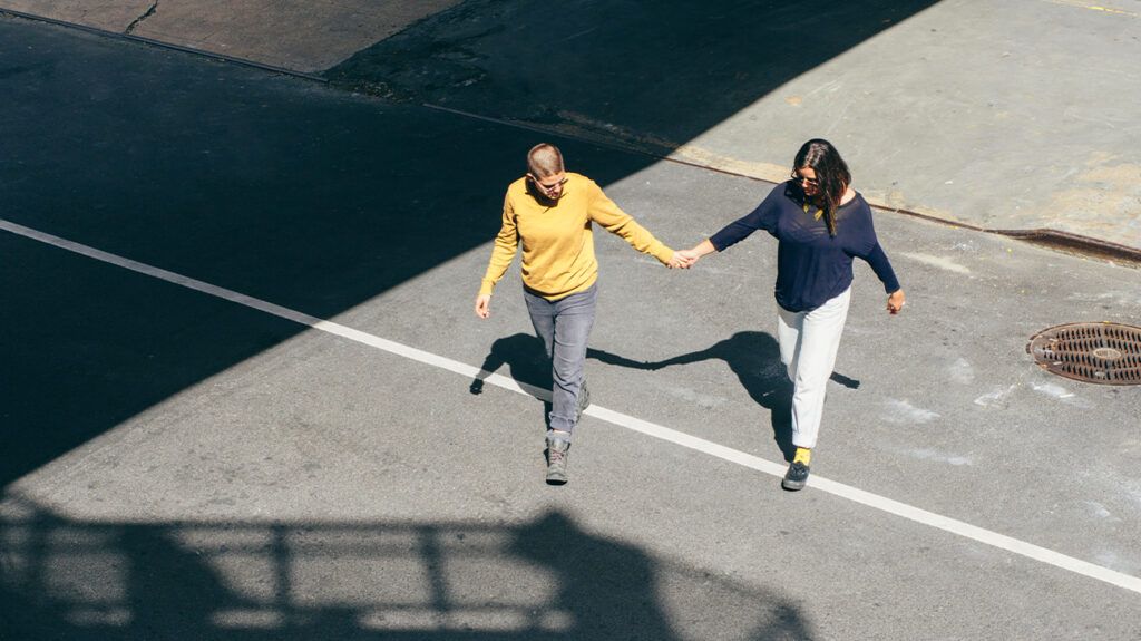 Couple holding hands walking across the street