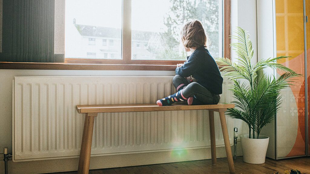 child sitting on a bench by the window