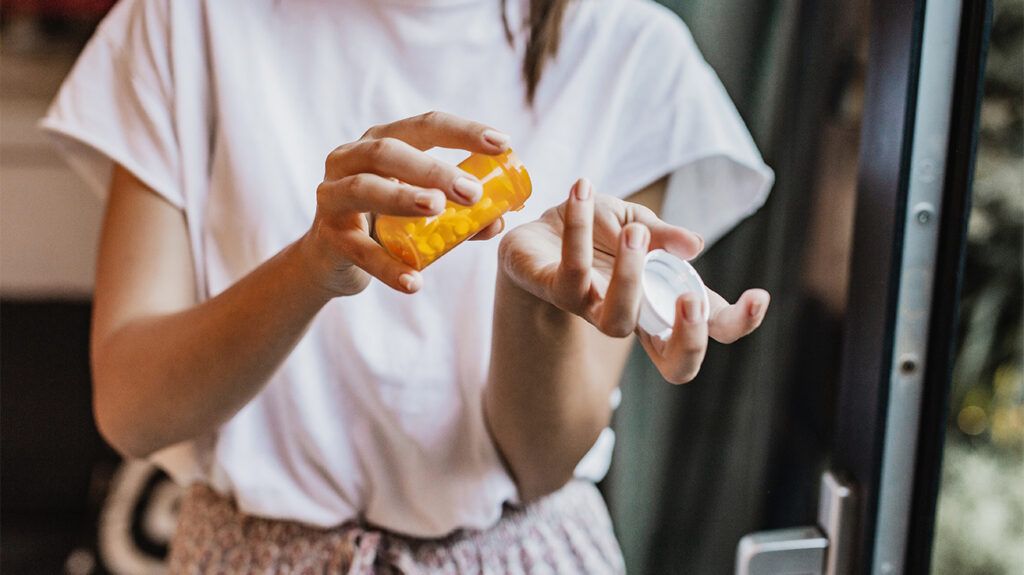 Woman pouring pills into hand