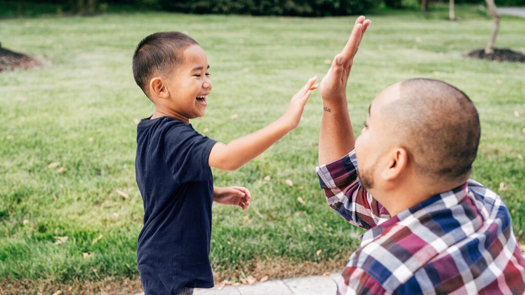 Supportive dad high-fiving his son