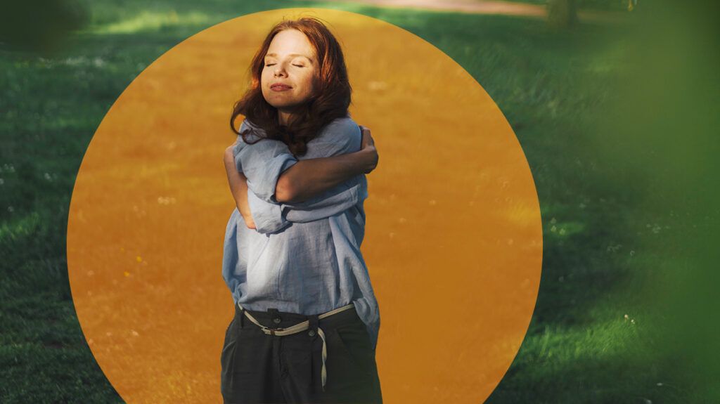 Woman hugging herself in the park